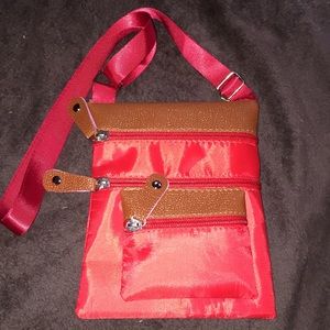 A small red traveling/crossbody/shoulder bag